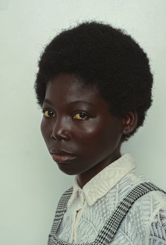 Beautiful Nigerian woman with big natural hair , posed model shoot, editorial fashion. She wears a retro outfit . She is fierce , confident, and has a lovely dark skin.