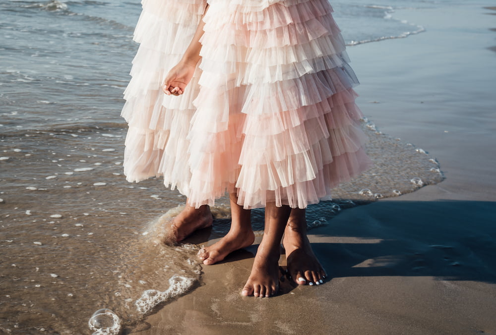 Mom and Daughter in matching dresses running on the beach during sunrise