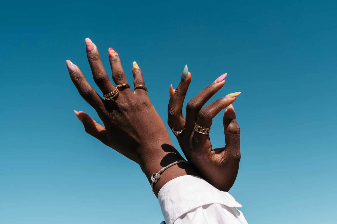 Colorful Nail Art Detail of the hands of a black woman with colorful nail art. Blue sky in the background.