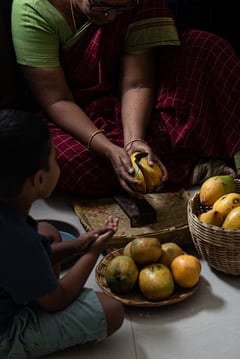 A kid excitedly watching his grandma slicing the fresh mango