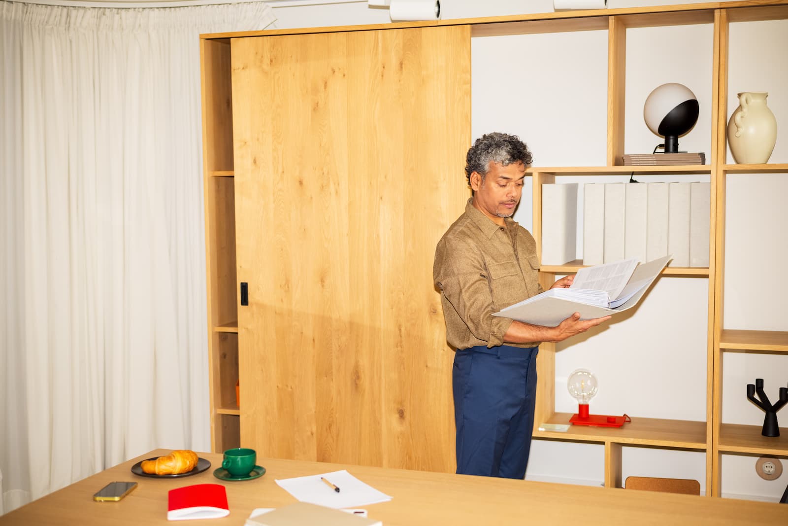 Middle-aged man standing in his office and reading some documents