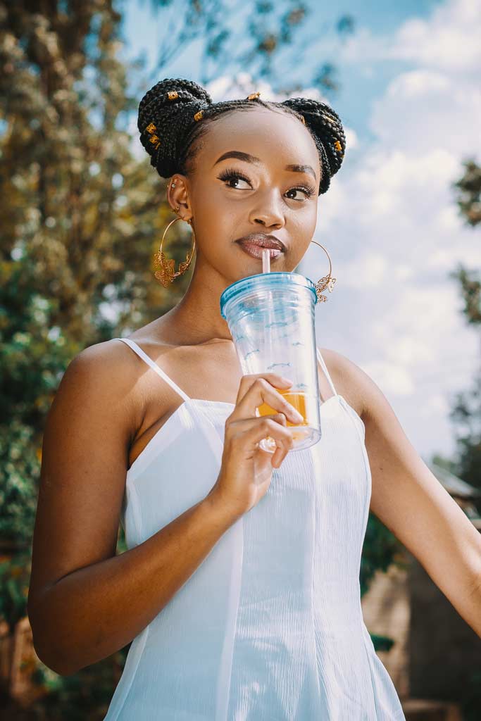 Woman enjoying a cold drink from a tumbler on hot summer's day.
