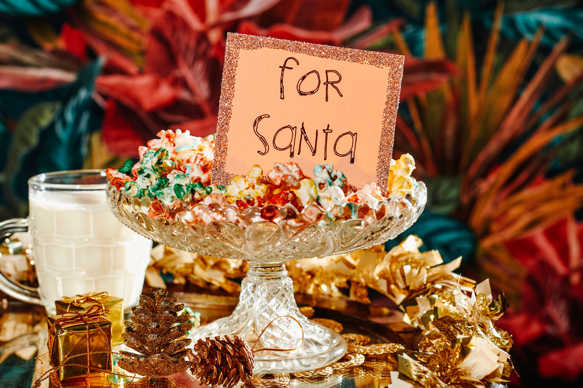 Treats and a handwritten note for Santa on a table ornamented with golden tinsel