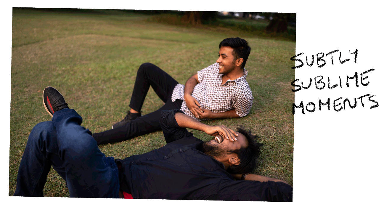 Two Friends Relaxing And Interacting Lying On Grass Ground. Text: Subtly sublime moments