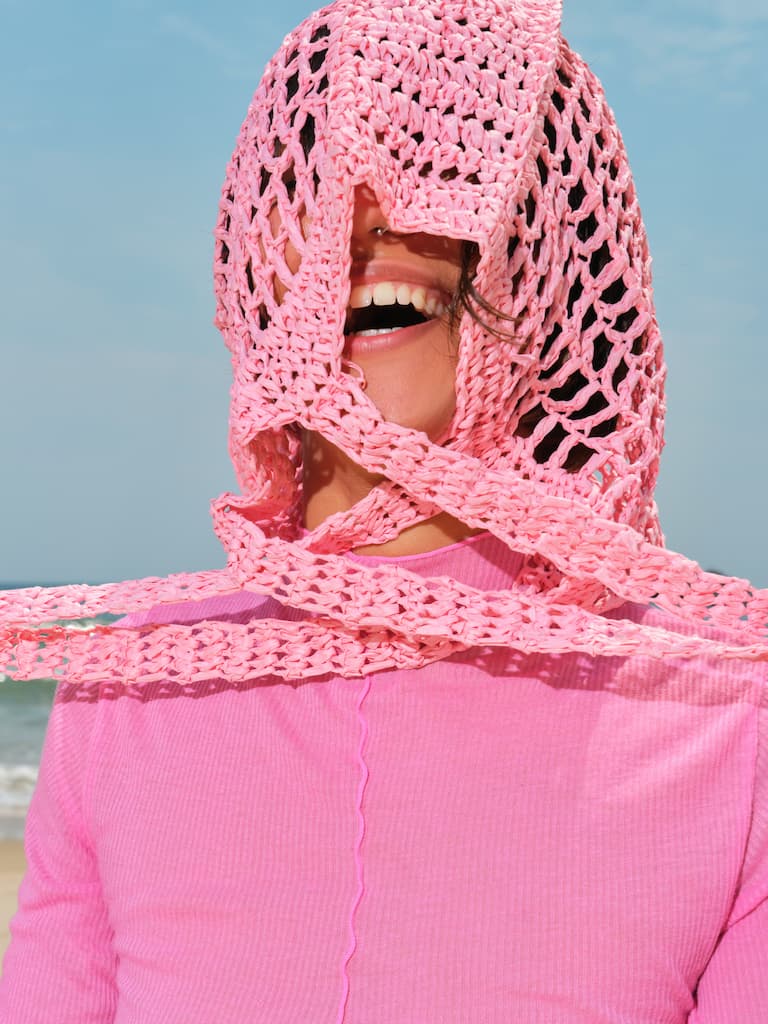 Happy Young Woman At The Beach with a book. Bright sun, pink and blue colors.