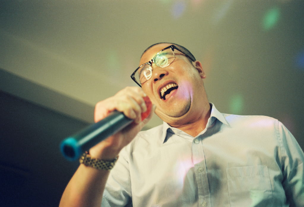 A Man Wearing Glasses Is Singing At Home
Holding the microphone