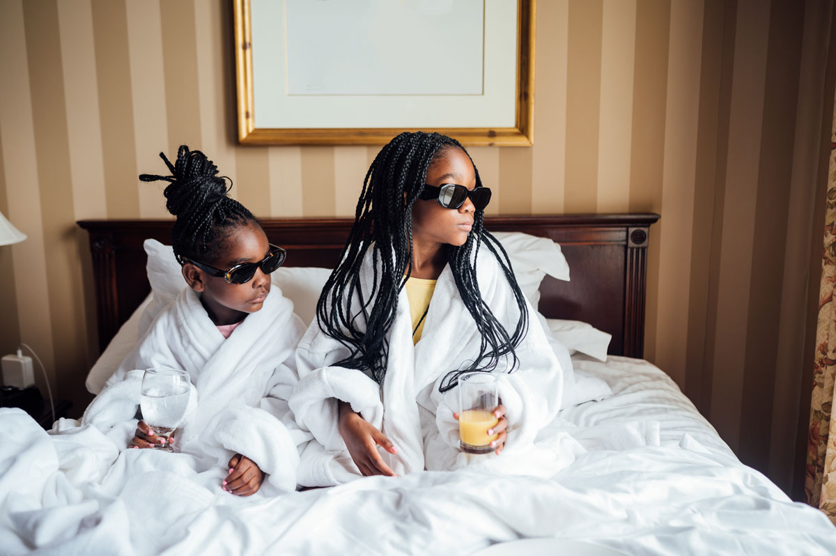 Sister laying in bed in robes enjoying room service for breakfast