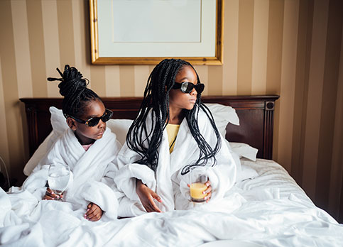 Two young girls in bed enjoying room service